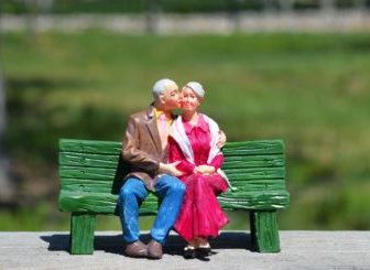 Figurines of older couple on bench