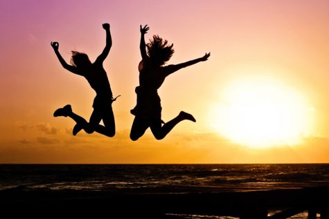Girls jumping up in the air in front of sunset