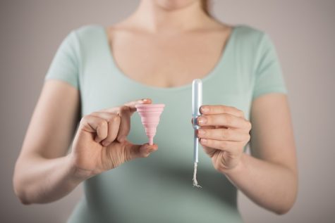 Woman holding tampon, menstrual cup