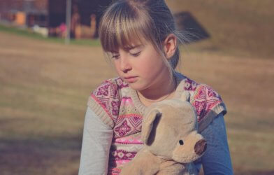 Sad girl holding teddy bear