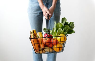 Shopper carrying basket of fresh vegetables