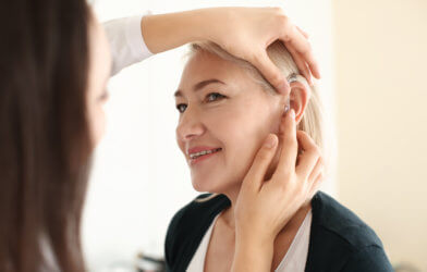 Hearing aid being put in woman's ear
