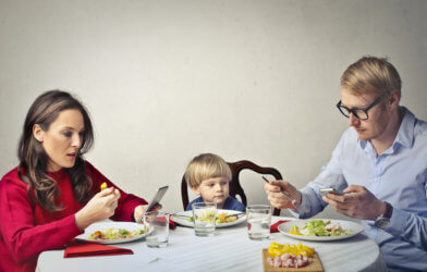 Parents looking at phones while eating dinner