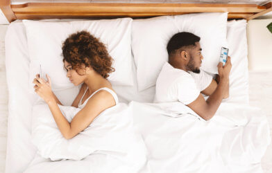Couple using their smartphones while in bed
