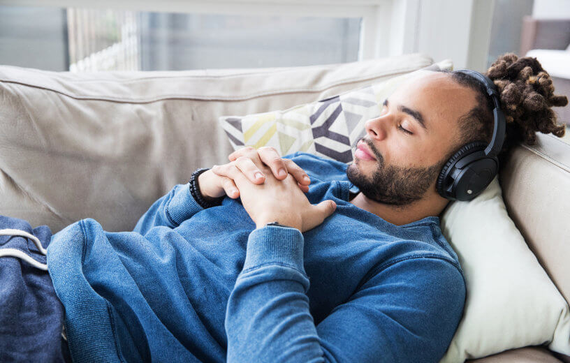 Man napping on the couch while listening to music