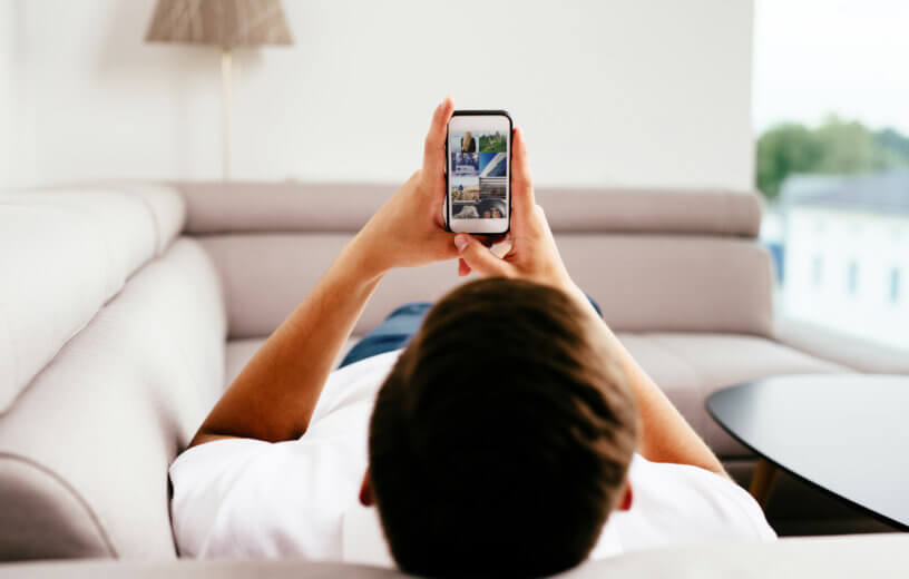 Man laying on couch looking at phone