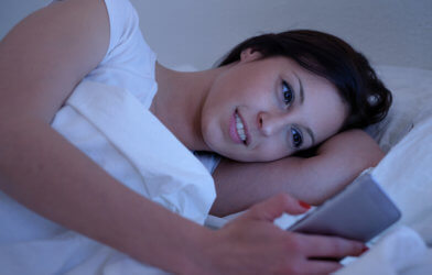 Woman texting in bed, possibly sexting