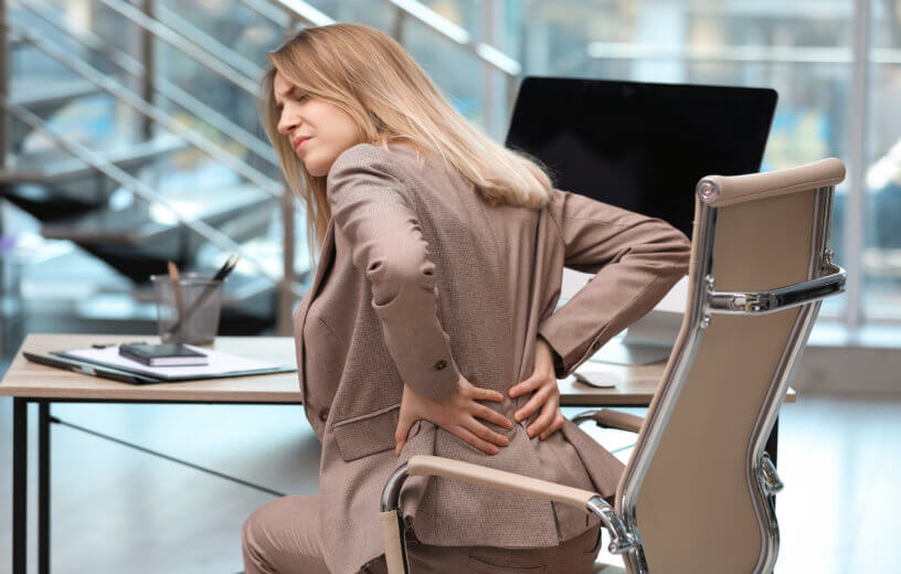 Woman battling lower back pain at office
