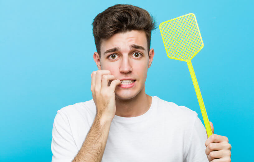 Man with fly swatter appearing nervous