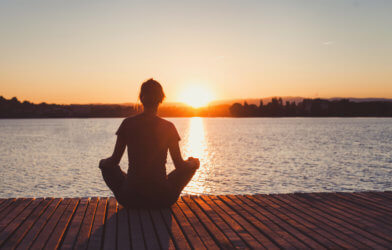 Woman practicing mindfulness meditation at sunset