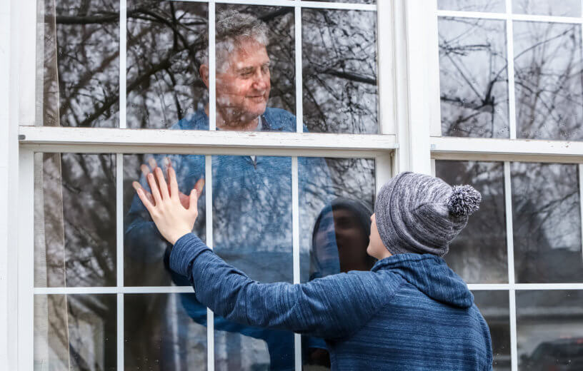 Social distancing - man at window during coronavirus lockdown