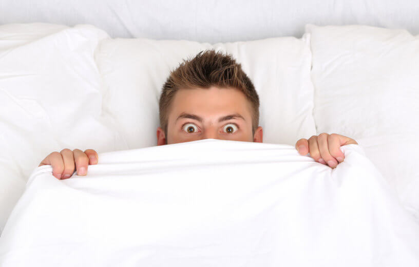 Scared man in bed having bad dream or nightmare