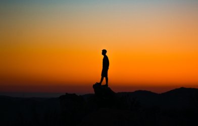 Person alone on cliff at sunset
