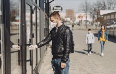 Man wearing face mask while entering store during COVID-19 / coronavirus outbreak