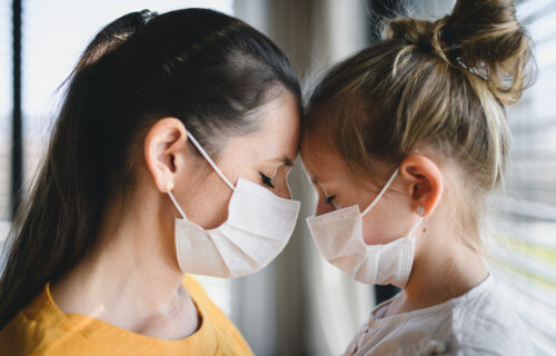 Mother, daughter wearing masks during coronavirus / COVID-19 outbreak, sad or grieving