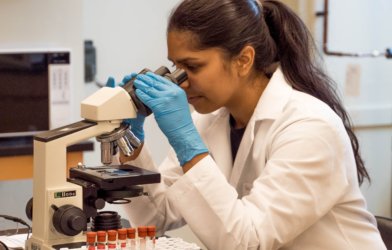 Scientist looking through microscope in lab