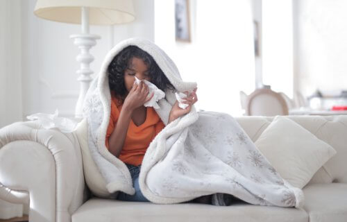 Woman sick on couch, blowing nose
