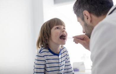 Doctor looking at sick child's throat, tonsils