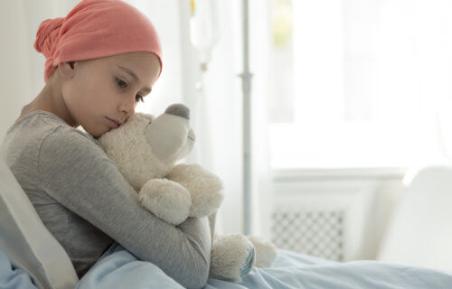 Young girl with cancer hugging teddy bear