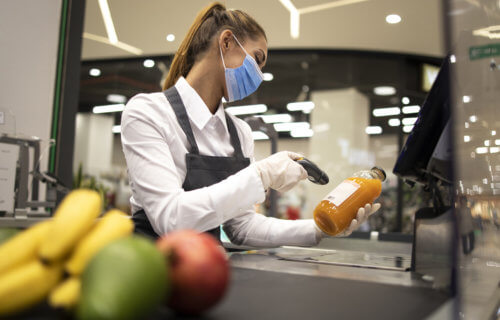 Grocery store cashier wearing face mask during coronavirus pandemic