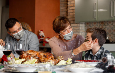 Family wearing face masks during Thanksgiving holiday dinner