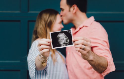 Pregnant woman, couple holding photo of ultrasound sonogram with baby