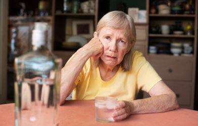 Older woman drinking alcohol alone