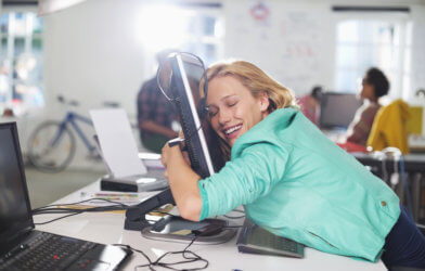 Woman hugging her office computer at work