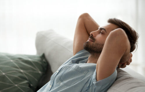 Man relaxing on couch alone, resting, happy