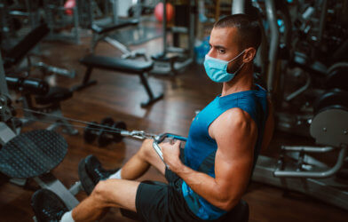 Athlete working out at gym in face mask during COVID pandemic