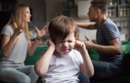 Parents fighting, arguing while scared child puts fingers in ears